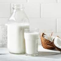 a glass of milk and a coconut on a counter