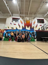 a group of people posing in front of a mural