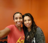 two women posing for a selfie in an orange room